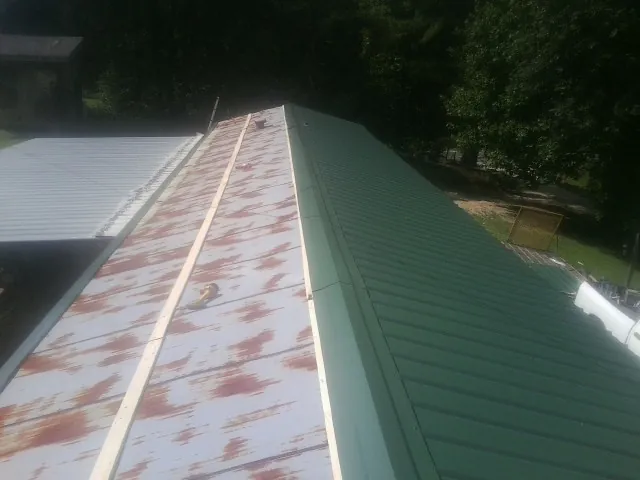 Old rusted panels beside newly installed green metal roofing — Wind Damage Roof Repair by Roofing Brothers in Blue Mountain