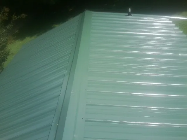 New green metal panels meeting at the ridge of a roof — Flat Roof Repair work by our crew in Blue Mountain