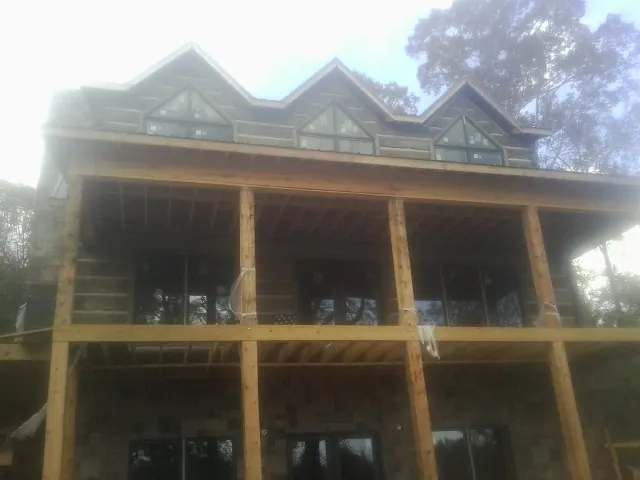 Dormers and porch framing on a large log home under construction — Roof Coating work by our crew in Blue Mountain