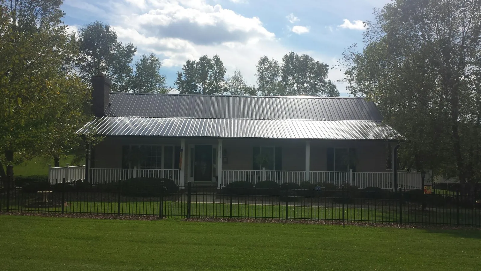 Gray metal roof on a brick ranch with a full width front porch — Gutter Guard Installation work by our crew in Blue Mountain