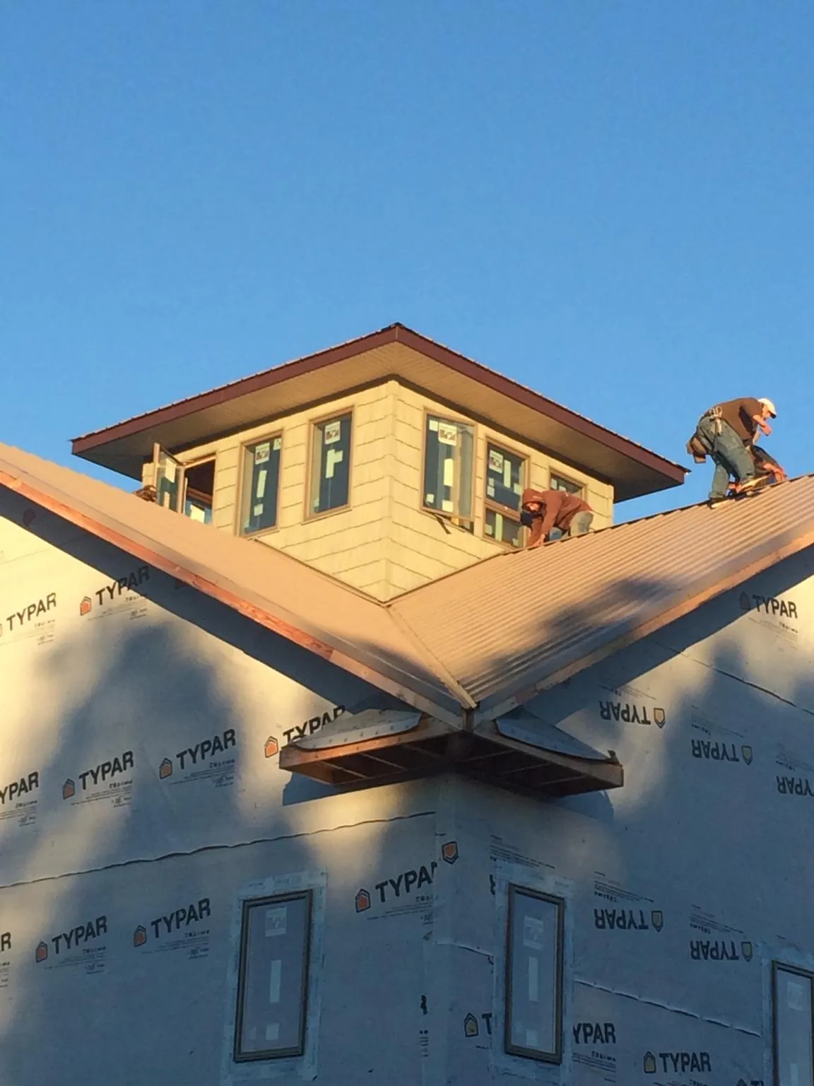 Roofers working around a rooftop cupola on a new metal roof at sunset — Roof Waterproofing in Blue Mountain by Roofing Brothers